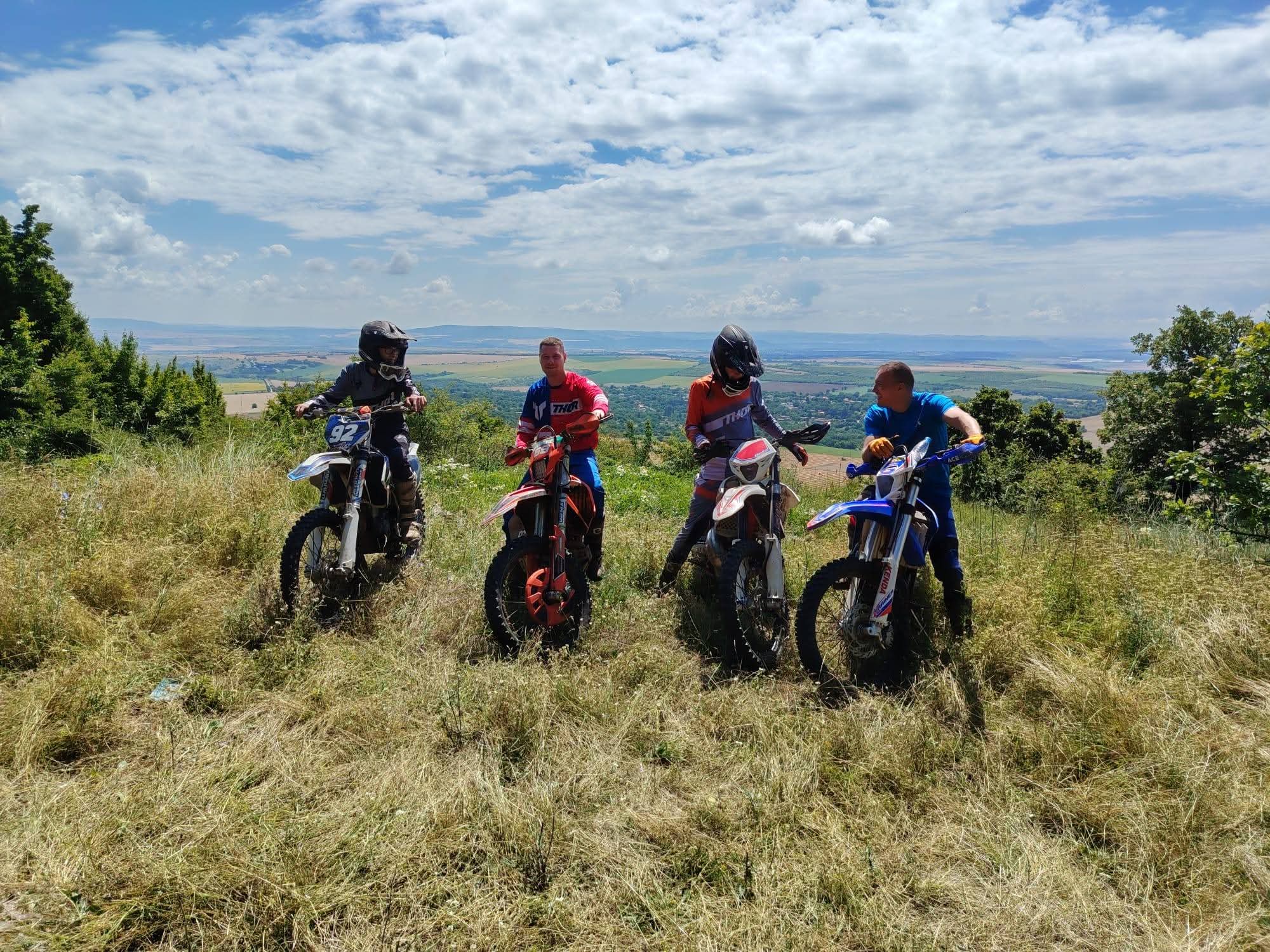 Group of enduro riders on a Bulgarian hilltop with valley views